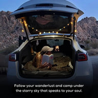 Tesla Model Y parked at a scenic campsite with camping gear and outdoor setup